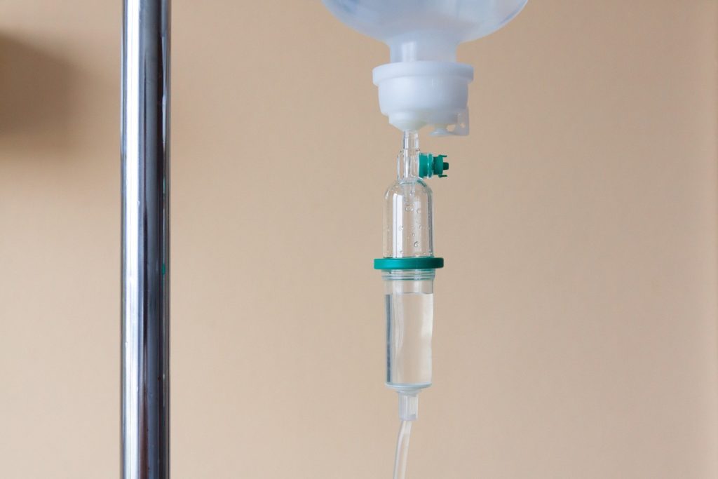 Infusionsflasche mit Vitamin C Infusion haengt an einem Infusionsstaender